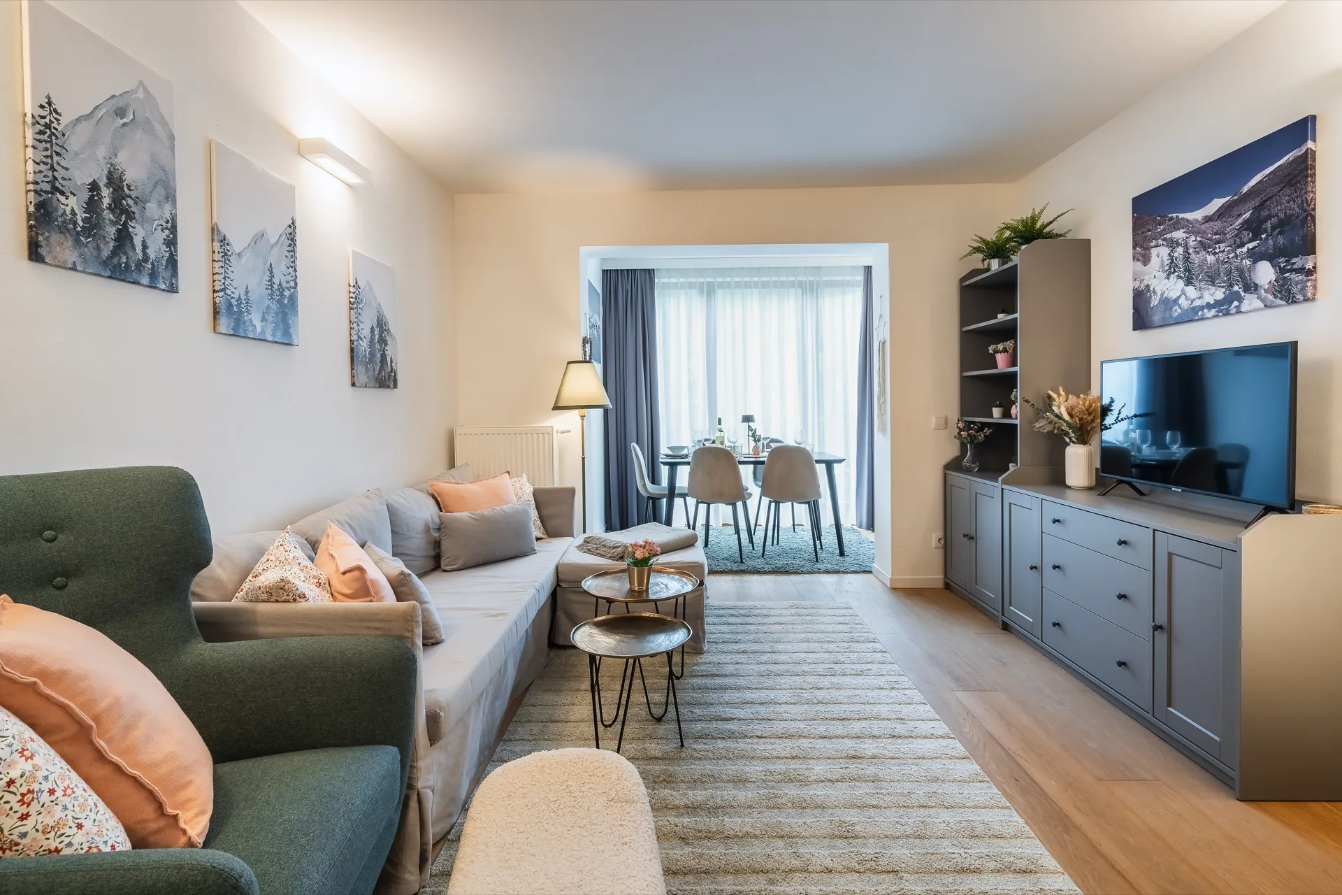 Modernes Wohnzimmer mit grünem Sofa, orange Akzenten und Bergkunst im Alpstay Chalet Nr. 2 Kärnten – professionelle Ferienwohnung Fotografie