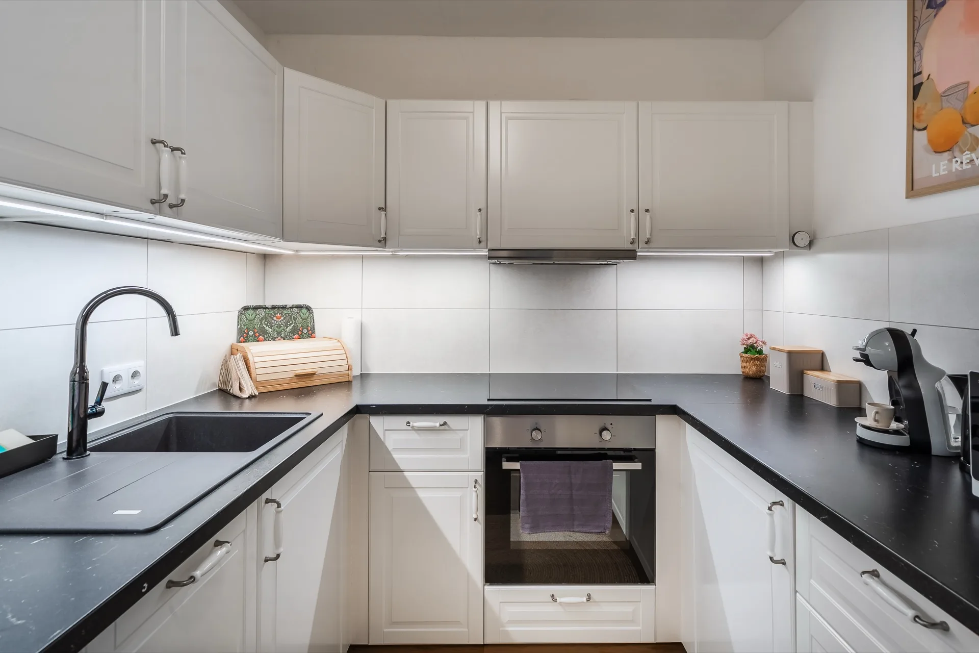 Vollausgestattete weiße Einbauküche mit schwarzer Arbeitsplatte, Backofen, Nespresso-Maschine und Herdplatten im Alpstay Chalet Nr.1 Bad Kleinkirchheim – Küchenfotografie Ferienwohnung Kärnten