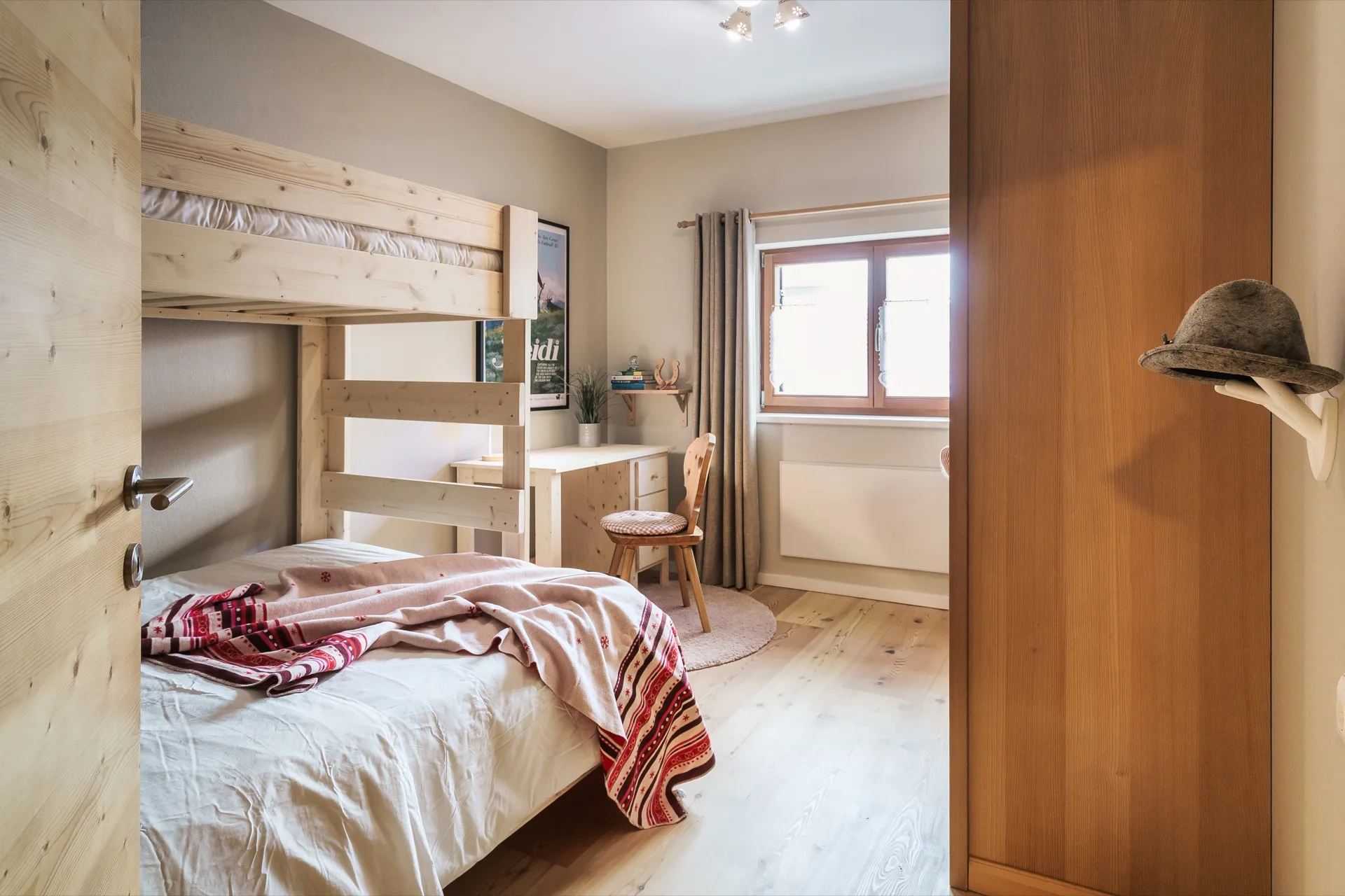 Helles Kinderzimmer mit Etagenbett aus hellem Holz, Schreibtisch und alpinen Dekorationen in der Ferienwohnung Holländer Kärnten – familienfreundliche Ferienwohnung Fotografie